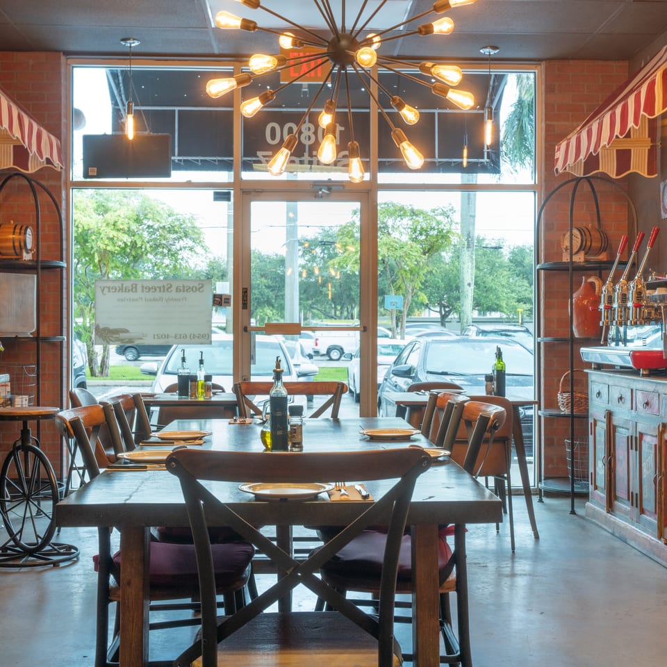 Cozy restaurant interior with wooden tables, chairs, brick walls, and a unique sputnik chandelier.