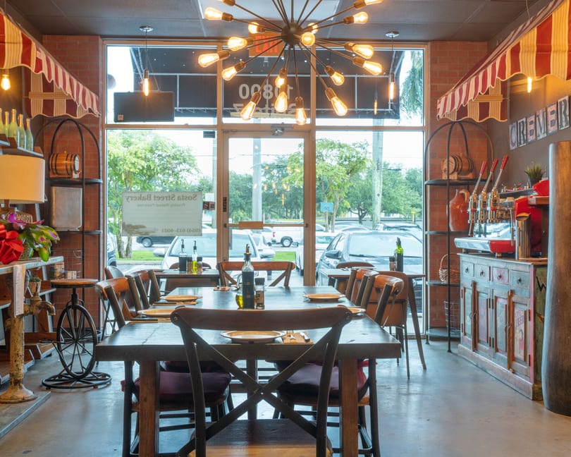 Cozy restaurant interior with wooden tables, chairs, brick walls, and a unique sputnik chandelier.